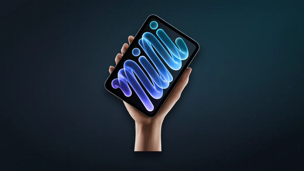 New iPad mini held in one hand, showing a colourful mini wallpaper