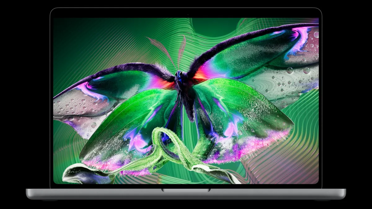 MacBook Pro with PROLED XDR Display showing a colourful butterfly on its OLED screen